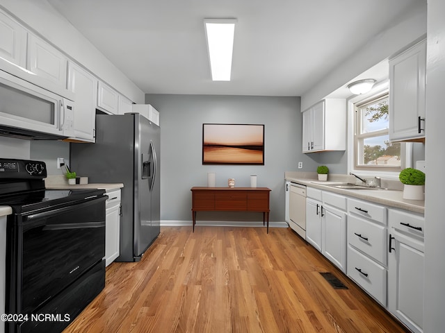 kitchen with sink, white cabinetry, light hardwood / wood-style flooring, and white appliances