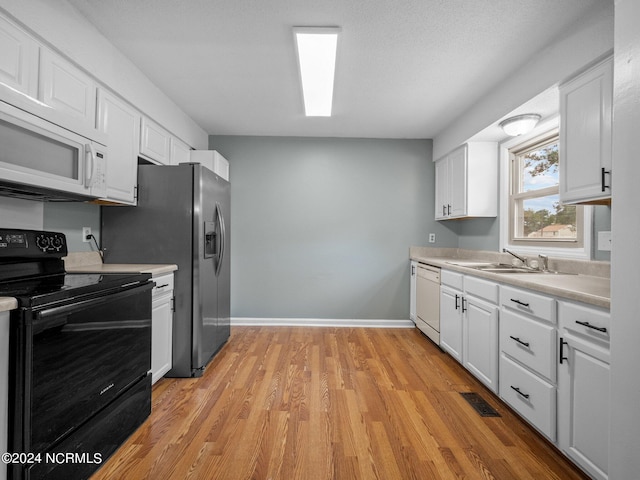 kitchen featuring white cabinetry, light hardwood / wood-style floors, white appliances, and sink