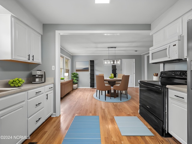 kitchen featuring light wood-type flooring, black / electric stove, radiator, and white cabinets