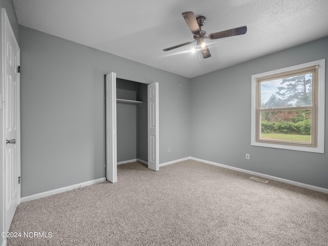 unfurnished bedroom with carpet flooring, a textured ceiling, a closet, and ceiling fan