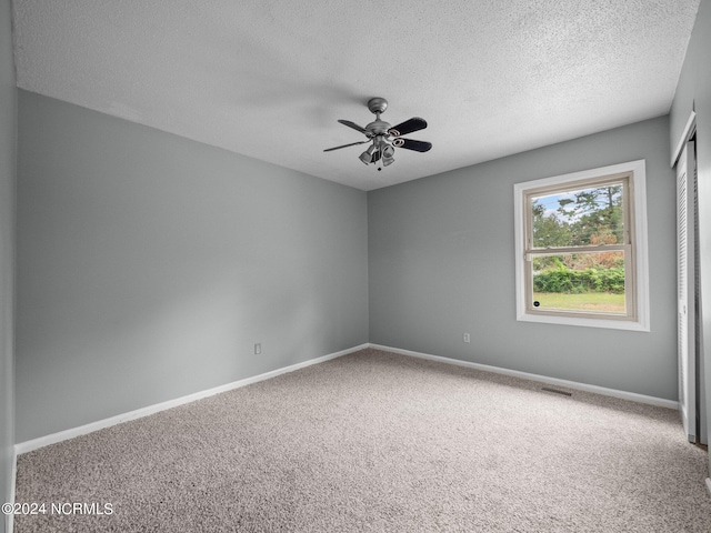 unfurnished room with carpet flooring, a textured ceiling, and ceiling fan