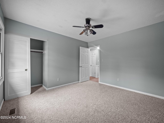 unfurnished bedroom with a closet, a textured ceiling, ceiling fan, and carpet floors