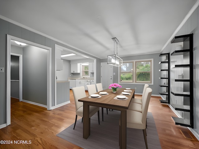 dining area featuring ornamental molding, light hardwood / wood-style flooring, and a chandelier