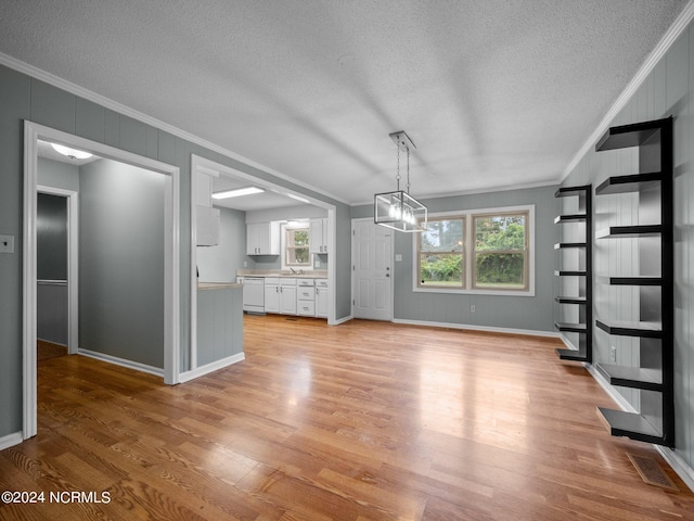 unfurnished living room featuring ornamental molding, a notable chandelier, and light hardwood / wood-style flooring