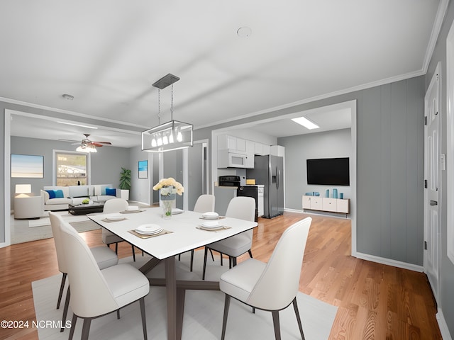 dining area with a ceiling fan, crown molding, light wood-style flooring, and baseboards