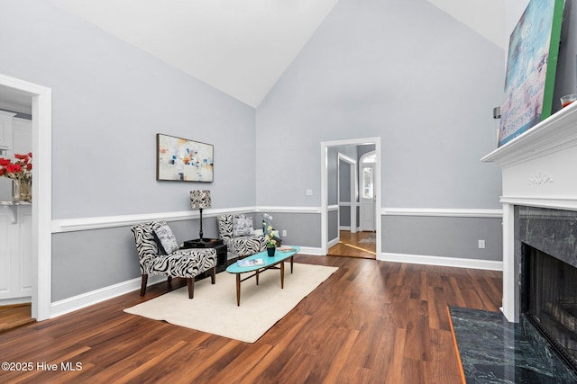 living area featuring high vaulted ceiling, dark hardwood / wood-style floors, and a high end fireplace