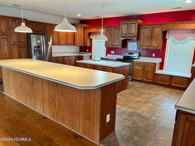 kitchen featuring a kitchen island, pendant lighting, light hardwood / wood-style flooring, and stainless steel appliances