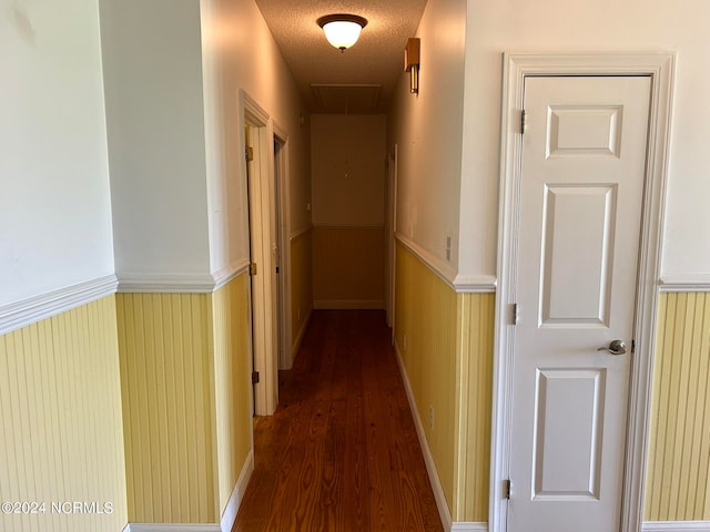 hall featuring dark wood-type flooring and a textured ceiling