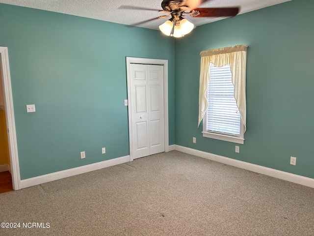 unfurnished bedroom with a textured ceiling, ceiling fan, carpet flooring, and a closet