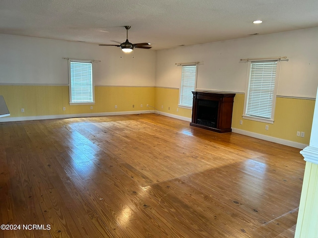 unfurnished living room featuring a wealth of natural light, ceiling fan, and hardwood / wood-style floors