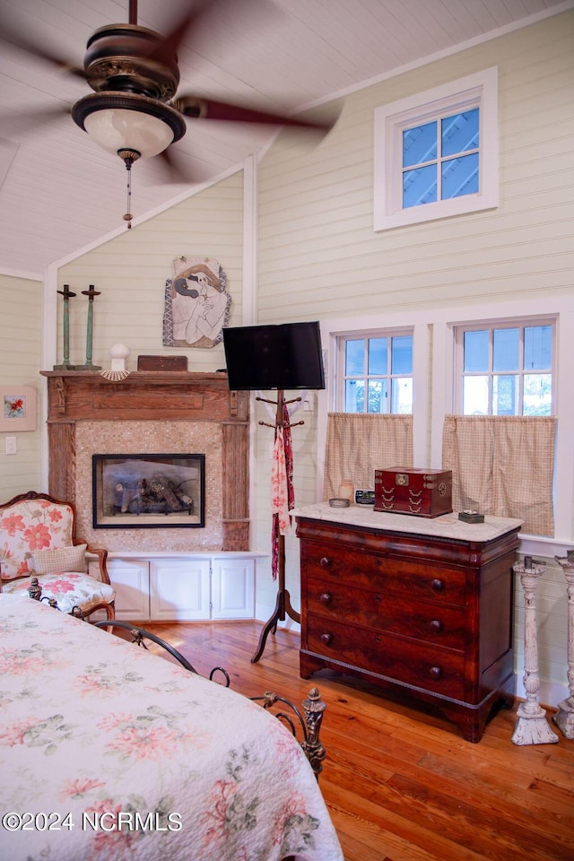 bedroom featuring a high ceiling, wood walls, ceiling fan, and hardwood / wood-style flooring