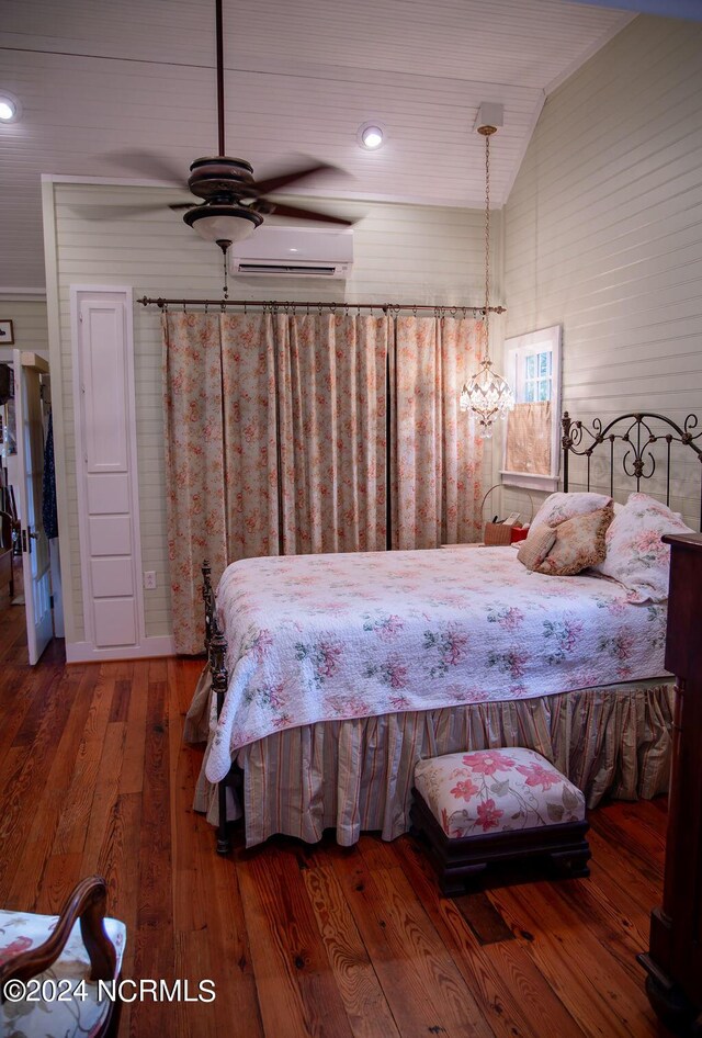 bedroom featuring ceiling fan with notable chandelier, vaulted ceiling, hardwood / wood-style flooring, and an AC wall unit