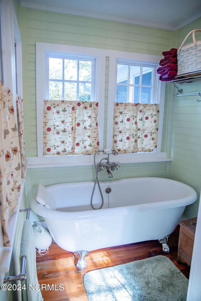 bathroom with a tub to relax in and hardwood / wood-style flooring