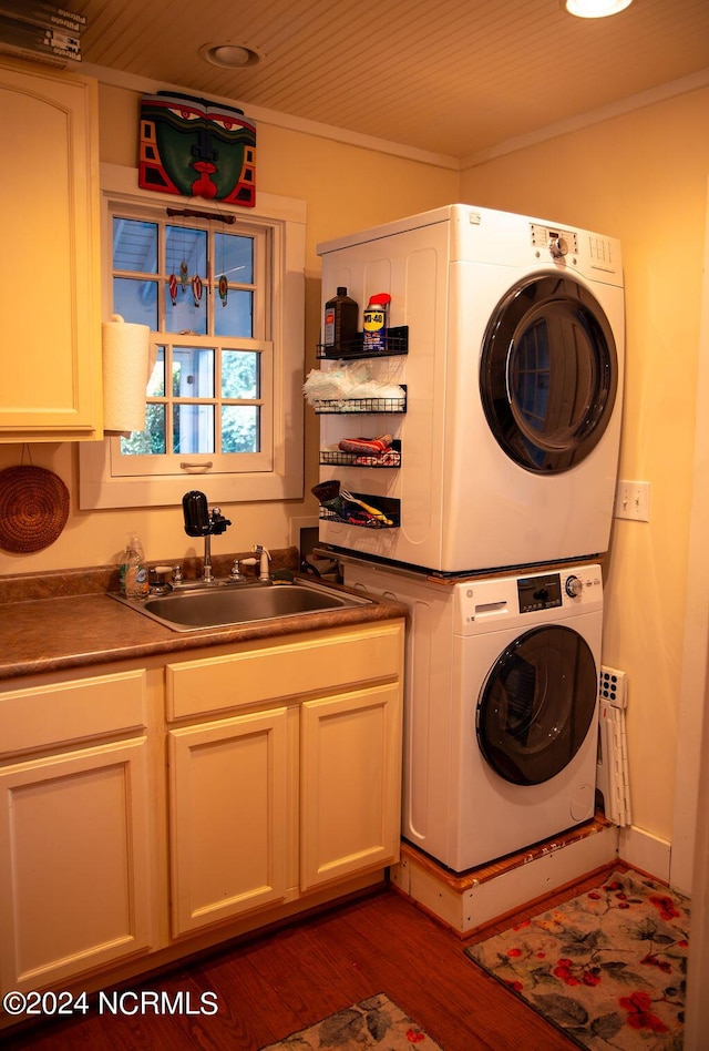 laundry area featuring sink, cabinets, ornamental molding, stacked washer / drying machine, and dark hardwood / wood-style flooring