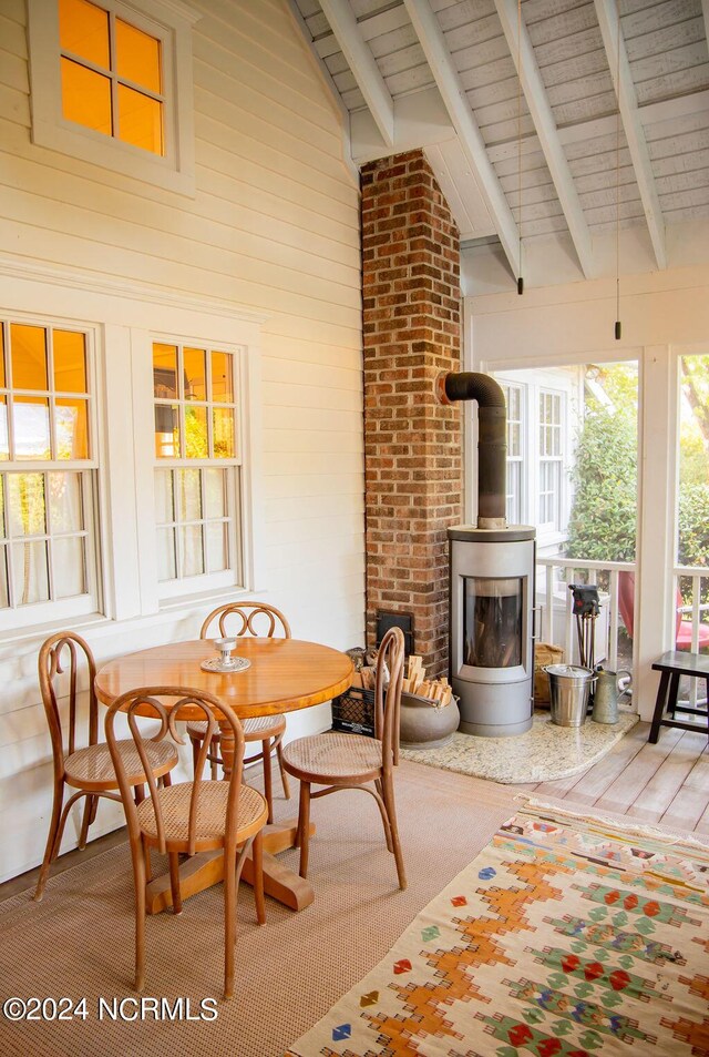 dining room with wood ceiling, high vaulted ceiling, a wood stove, and beamed ceiling