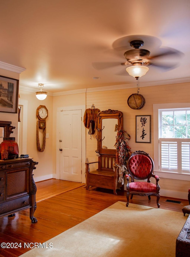 living area featuring hardwood / wood-style flooring, ceiling fan, and ornamental molding