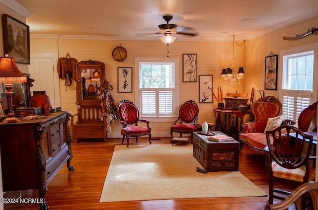 sitting room with ceiling fan with notable chandelier, ornamental molding, and light hardwood / wood-style flooring