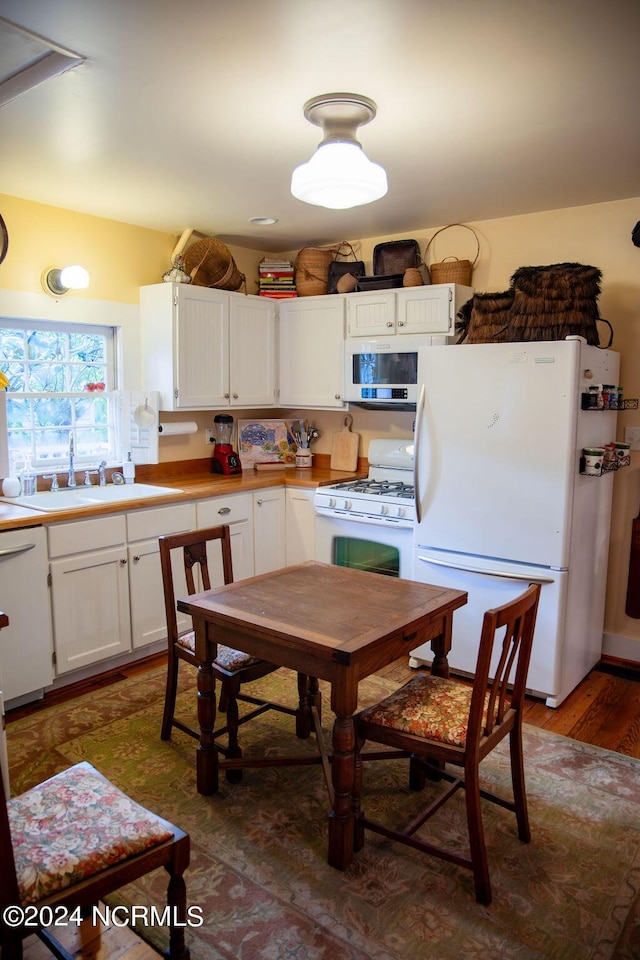 kitchen featuring white appliances, dark hardwood / wood-style flooring, white cabinetry, and sink