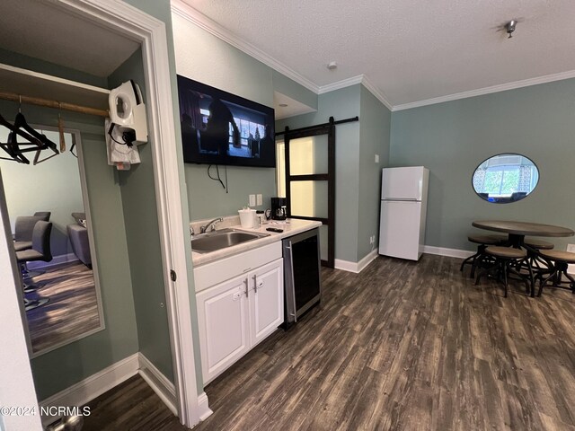 kitchen with dark wood-type flooring, sink, white cabinetry, white refrigerator, and a barn door