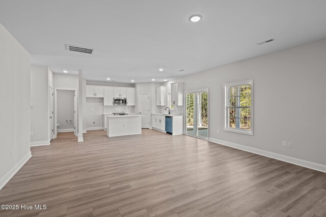 unfurnished living room featuring sink and light hardwood / wood-style flooring