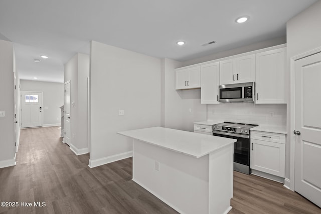 kitchen with a kitchen island, appliances with stainless steel finishes, backsplash, white cabinets, and dark hardwood / wood-style flooring