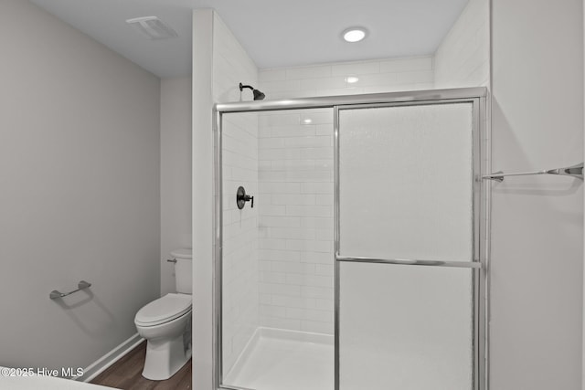 bathroom featuring walk in shower, toilet, and hardwood / wood-style floors