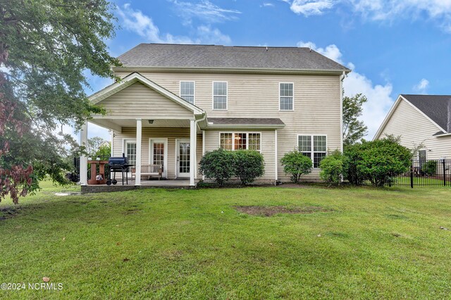 rear view of house with a patio and a lawn