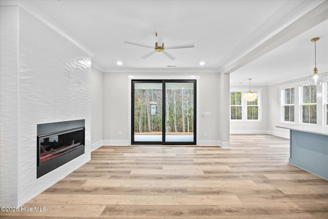 unfurnished living room featuring ornamental molding, a tiled fireplace, light wood-type flooring, and a wealth of natural light