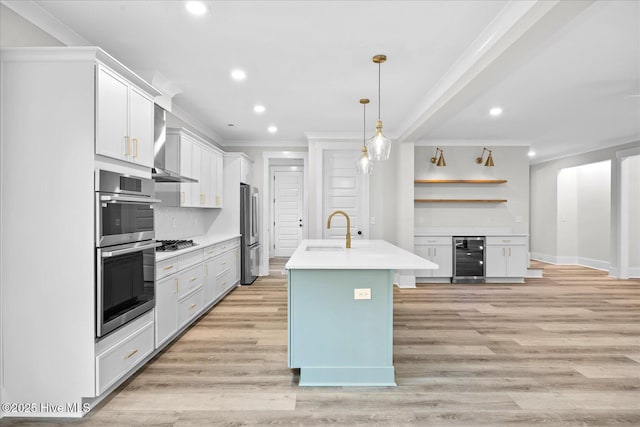 kitchen featuring ornamental molding, a kitchen island with sink, sink, and white cabinets