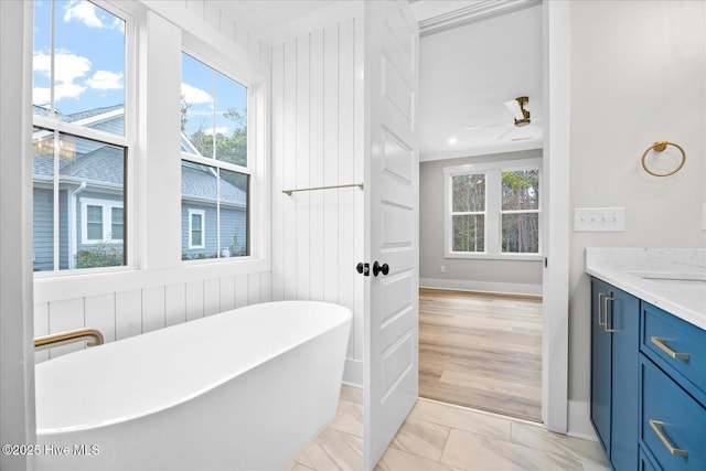 bathroom featuring a washtub, vanity, a wealth of natural light, and ceiling fan