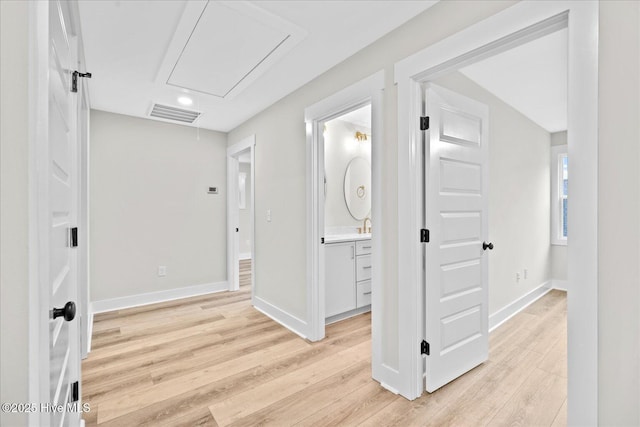 hallway with sink and light hardwood / wood-style flooring