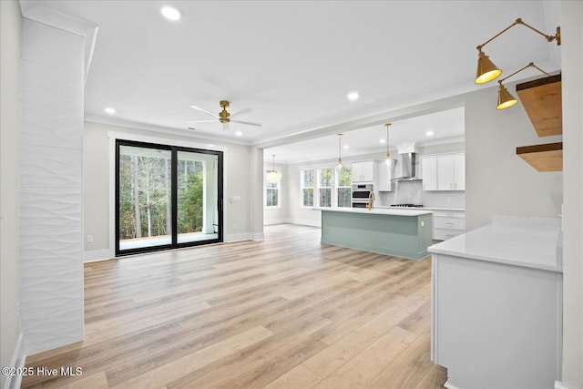 unfurnished living room featuring ornamental molding, ceiling fan, and light hardwood / wood-style floors