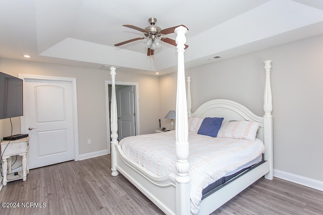 bedroom featuring ceiling fan, hardwood / wood-style flooring, and a raised ceiling