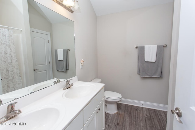 bathroom featuring vaulted ceiling, toilet, hardwood / wood-style flooring, and double sink vanity