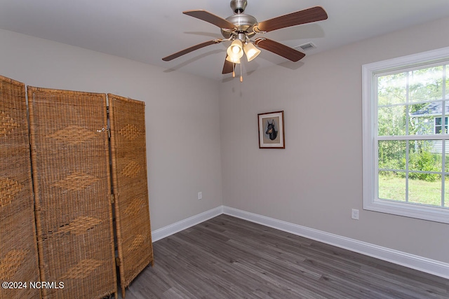 unfurnished room featuring a healthy amount of sunlight, ceiling fan, and dark wood-type flooring