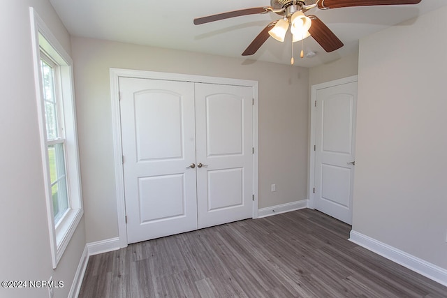 unfurnished bedroom featuring dark wood-type flooring, multiple windows, a closet, and ceiling fan