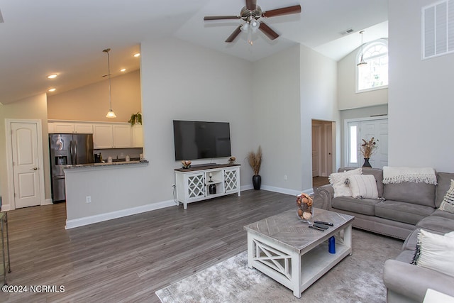 living room with dark hardwood / wood-style flooring, ceiling fan, and high vaulted ceiling