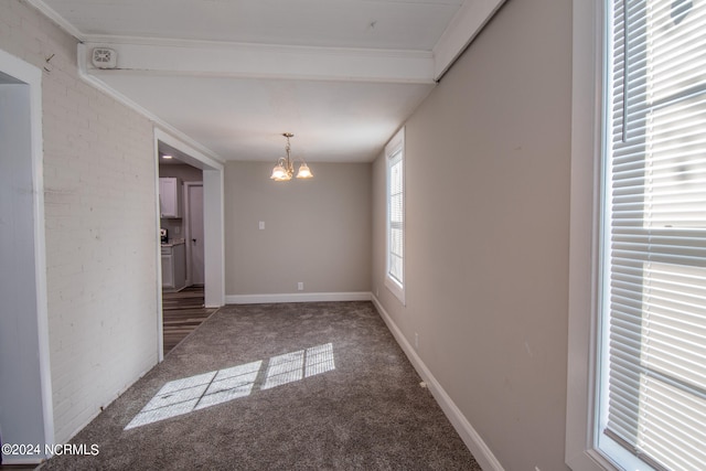 spare room with ornamental molding, a chandelier, brick wall, and carpet flooring