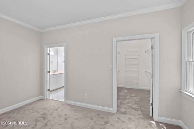 unfurnished bedroom with a spacious closet, light carpet, a closet, and ensuite bath