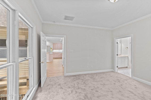 unfurnished bedroom featuring ensuite bath, ornamental molding, and light carpet