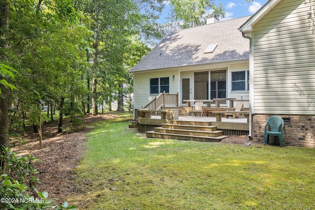 rear view of house with a wooden deck and a yard