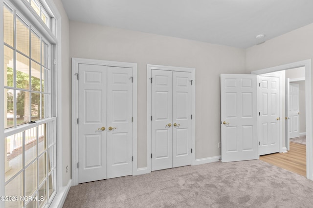 unfurnished bedroom with multiple closets and light colored carpet