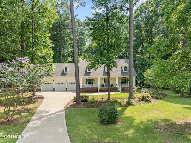 new england style home featuring a garage, a front lawn, and a porch