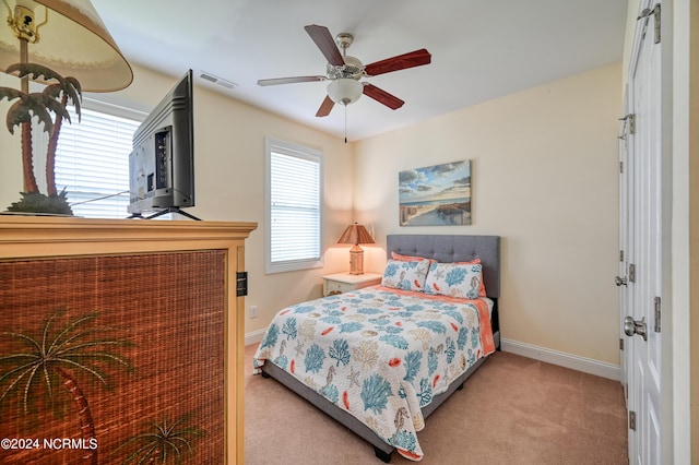 bedroom with light colored carpet, ceiling fan, and multiple windows