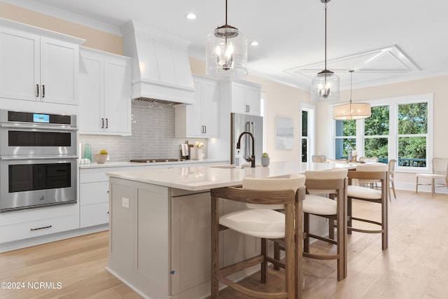 kitchen featuring a center island with sink, pendant lighting, white cabinets, and stainless steel appliances