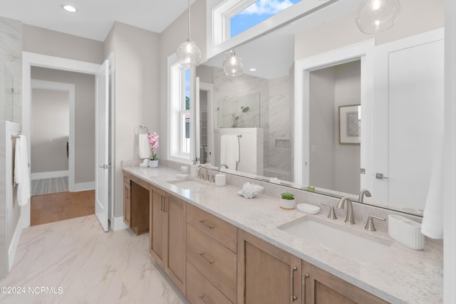 bathroom featuring tiled shower, vanity, and plenty of natural light