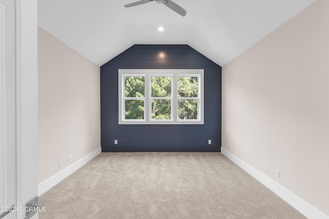 carpeted spare room featuring vaulted ceiling and ceiling fan