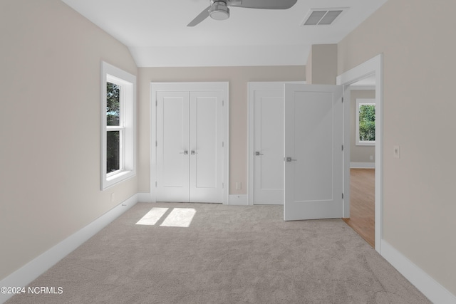 unfurnished bedroom with ceiling fan, light carpet, and vaulted ceiling