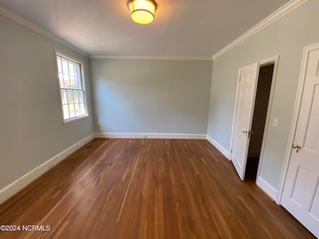 empty room with dark wood-type flooring and crown molding