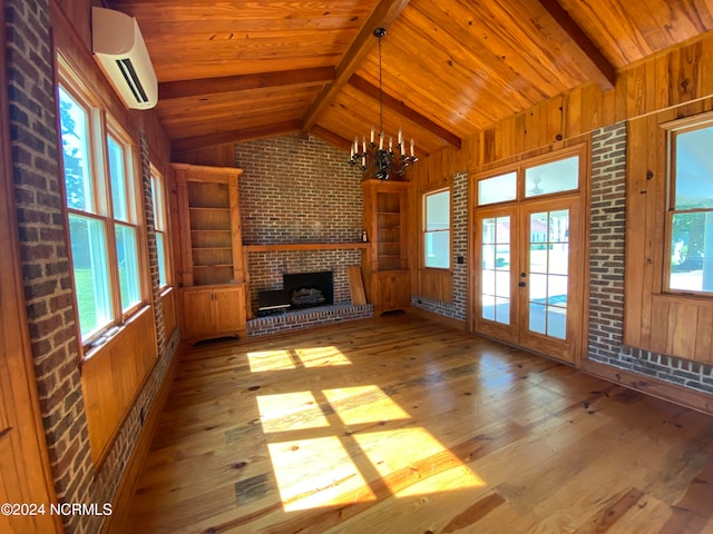 unfurnished living room featuring a wall mounted AC, a healthy amount of sunlight, a chandelier, and light wood-type flooring